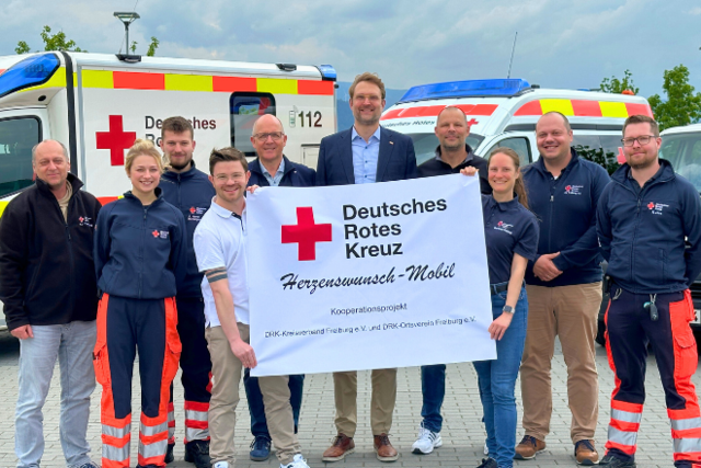 das Team des Herzenswunschmobils steht vor der Wunschmobilflotte