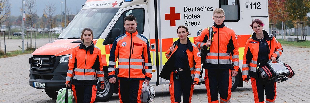 ein Team Notfallsanitäter läuft in Einsatzkleidung auf die Kamera zu