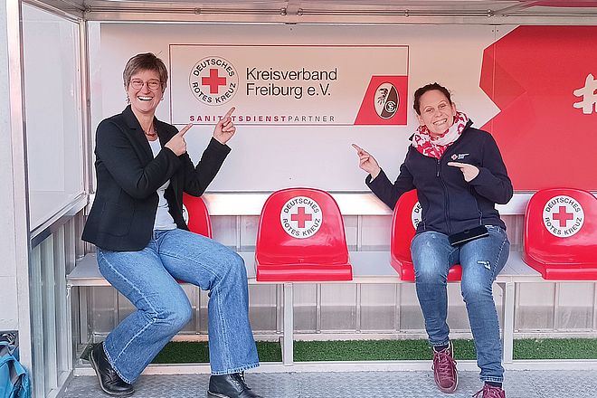 Die Leiterinnen des Projekts zeigen auf das Logo des DRK Kreisverbands