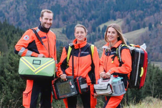 drei junge Sanitäterinnen schauen lächelnd in die Kamera, im Hintergrund sieht man den Schwarzwald