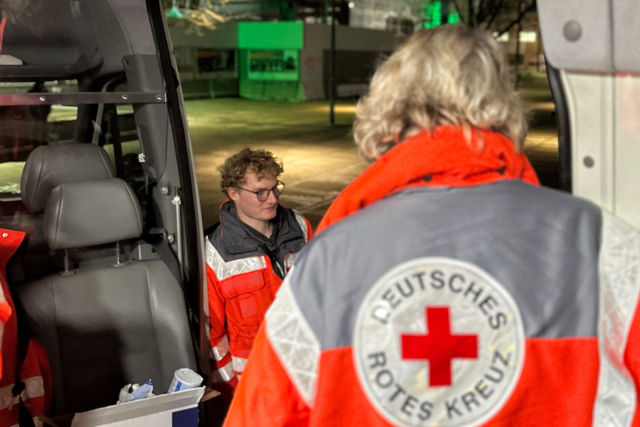 Zwei Ehrenamtliche Helfer stehen vor dem DRK-Kältebus