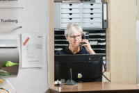 Frau sitzt am Empfang vor ihrem Computer und telefoniert