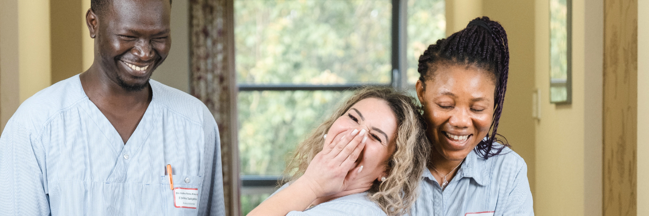 Drei Pfleger:innen lachen gemeinsam