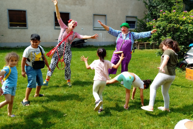 zwei Clowns spielen mit Kindern in einer Flüchtlingsunterkunft