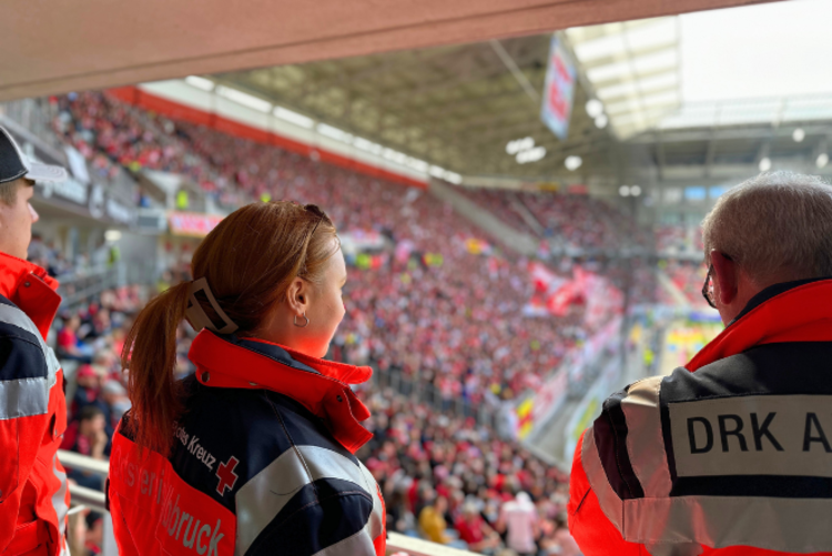 eine junge Sanitäterin blickt auf die feiernden Fans des SC Freiburg